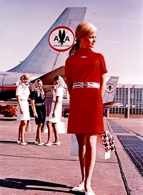 Tripulación de American Airlines en plataforma, vestido rojo de uniforme con un cinturón de rayas en la cintura