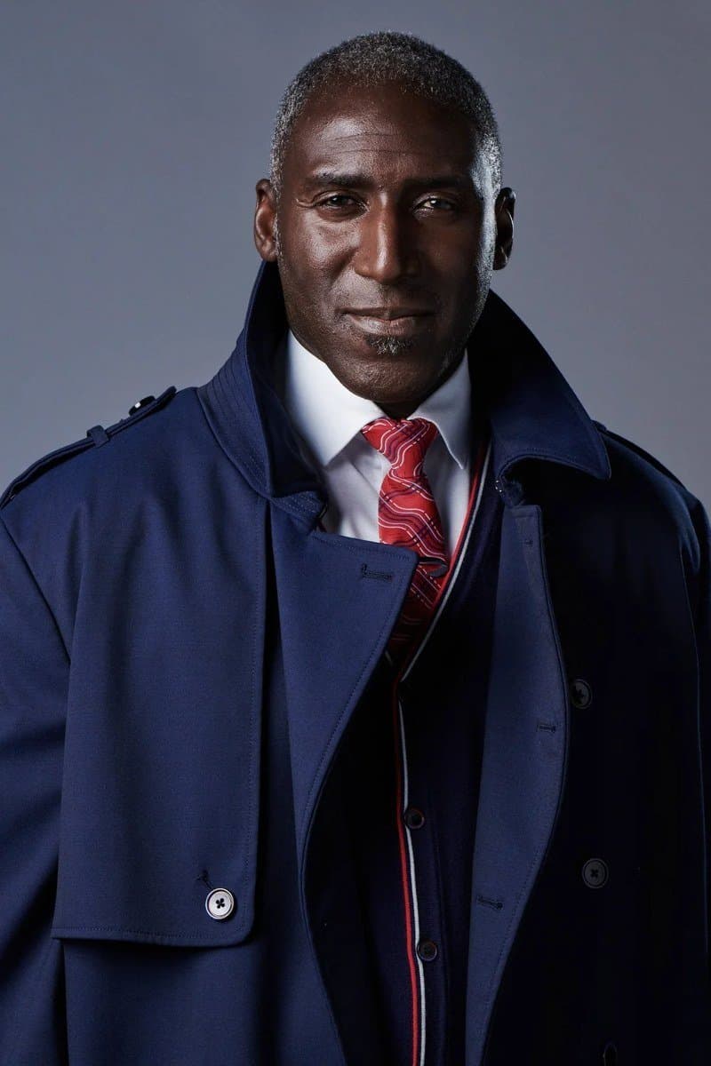 Uniforme de tierra de British Airways por Ozwald Boateng, abrigo marino sobre traje de tres piezas con corbata de rayas rojas