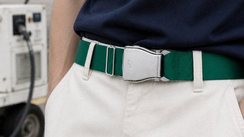 Ceinture d'avion AMAZONAS vert émeraude portée avec un pantalon blanc et un tee-shirt bleu marine, sur l'aire de stationnement