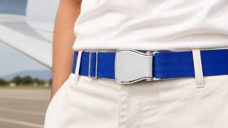 Ceinture d'avion PACIFIC bleu électrique portée avec un pantalon blanc sur le tarmac, à côté d'une aile d'avion