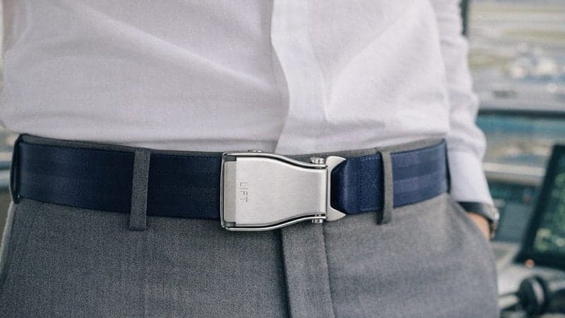 Ceinture d'avion TRANSATLANTIC bleu marine portée avec un pantalon de costume gris et une chemise blanche, dans une tour de contrôle