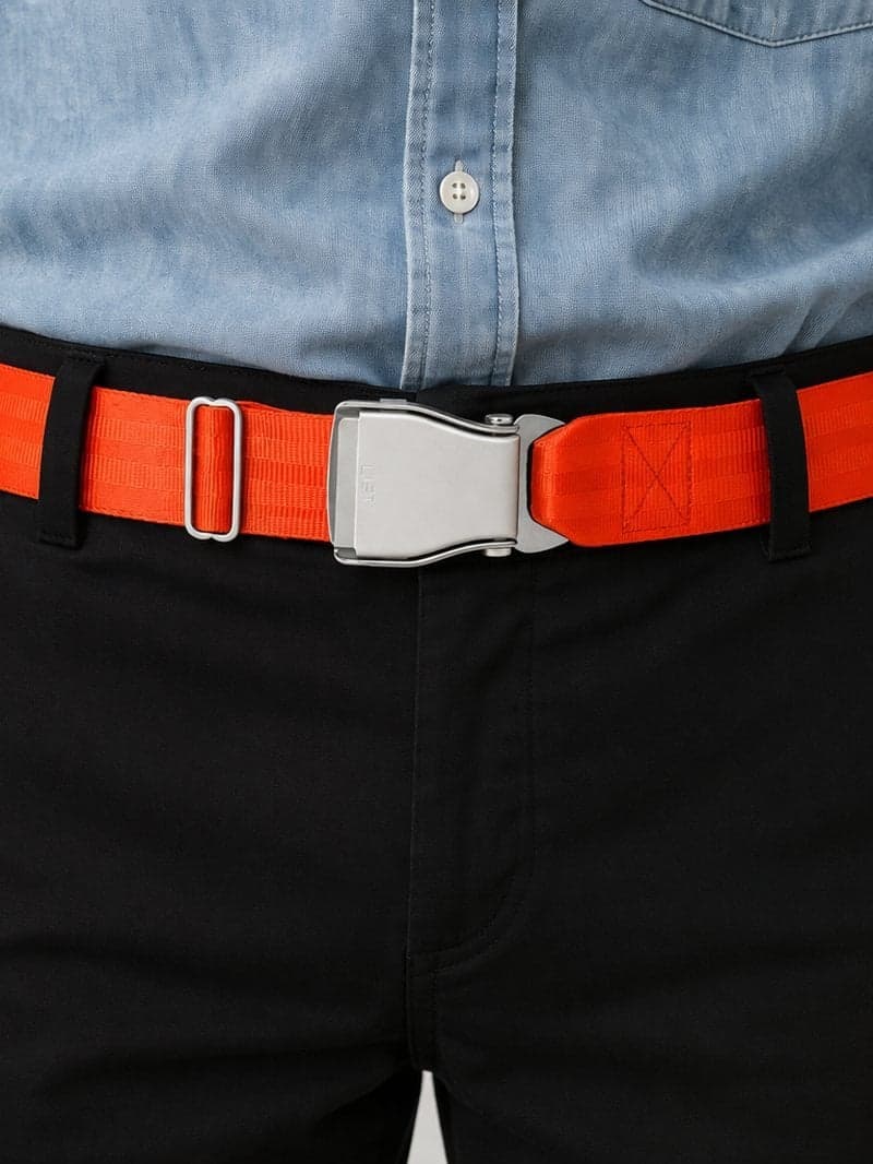Ceinture d'avion TROPIC orange signal portée avec un chino noir et une chemise en chambray