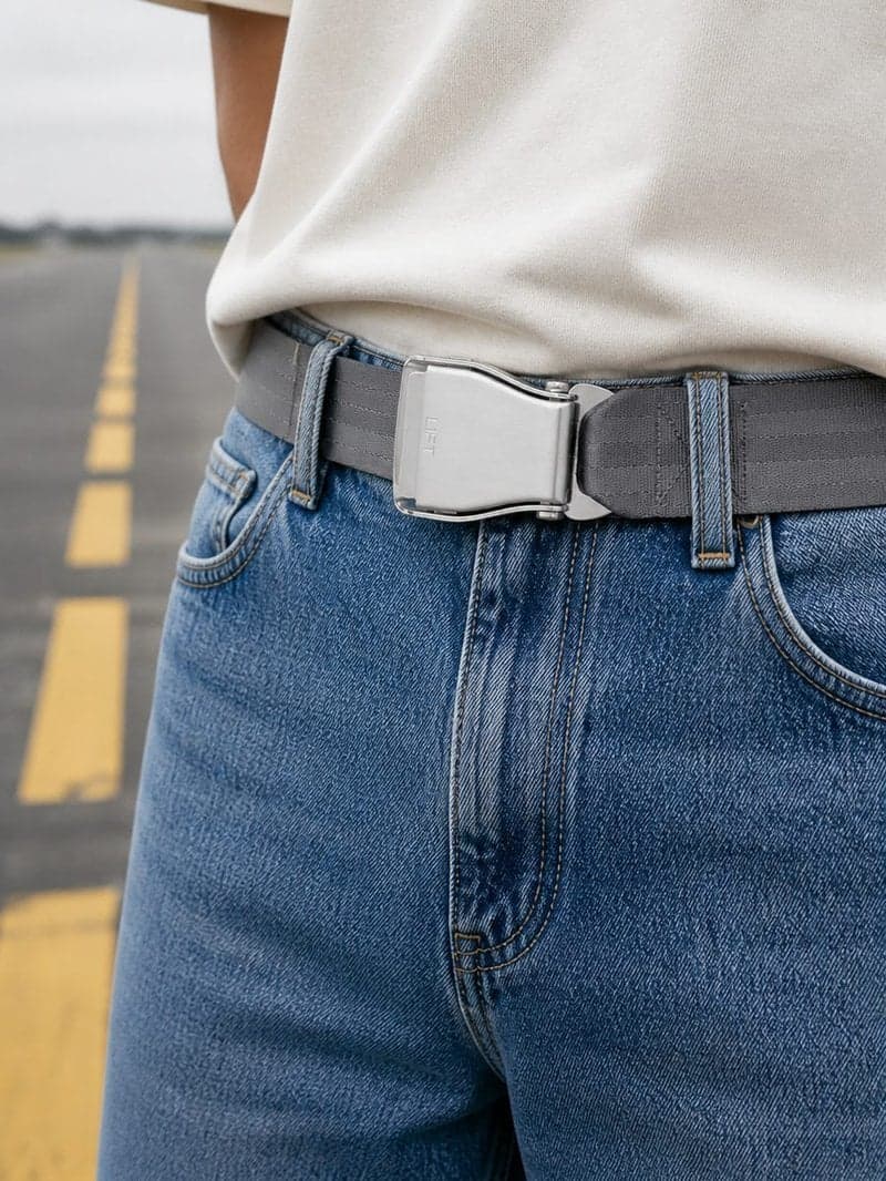 Ceinture d'avion RUNWAY grise portée avec un jean bleu clair et un tee-shirt crème sur une piste