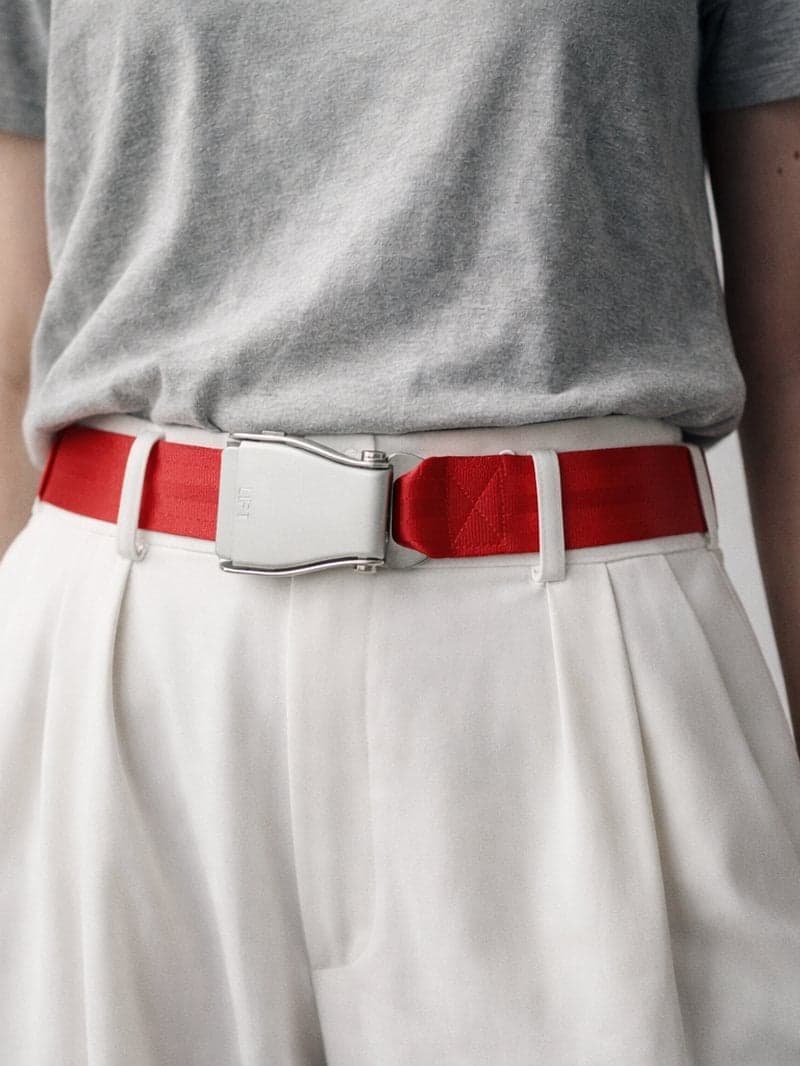 Ceinture d'avion AUSTRAL rouge profond portée par une femme avec un pantalon large blanc à pinces et un tee-shirt gris