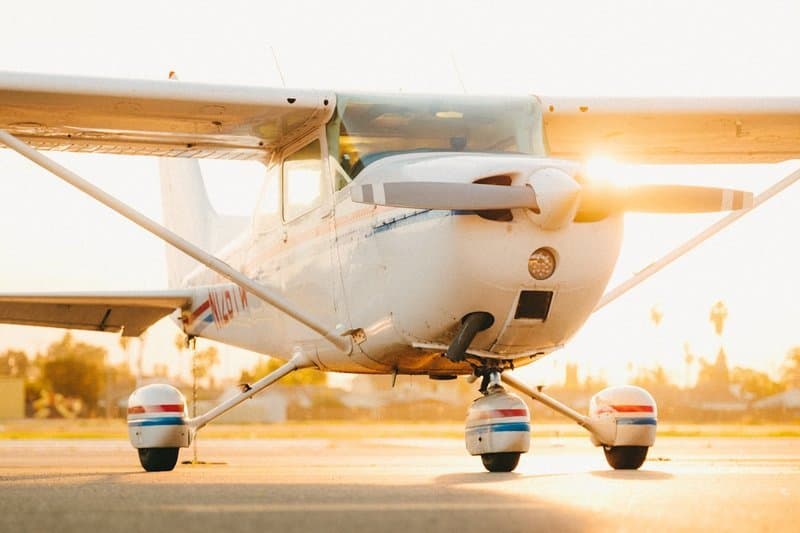 Eine weiße Cessna, einmotoriger Hochdecker, bei Sonnenuntergang auf dem Vorfeld