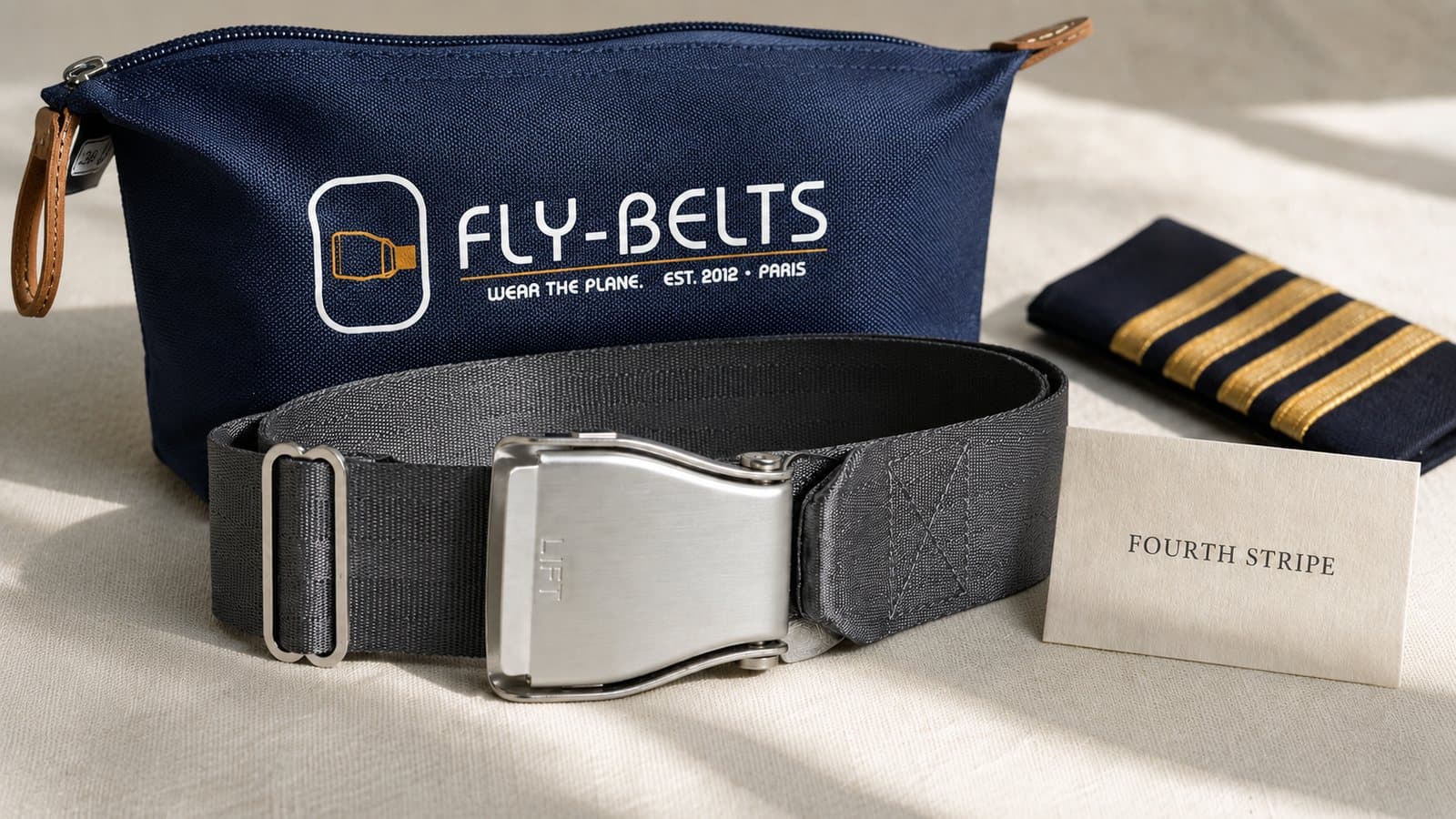 Ein grauer Aviation-Gürtel, ein marineblauer Fly-Belts Beutel und eine Kapitänsschulterklappe mit vier Streifen neben einer Karte mit der Aufschrift Fourth Stripe